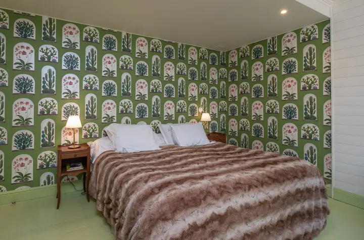 Chambre tapissée d'un papier peint vert à motifs, lit double et lampe de chevet
