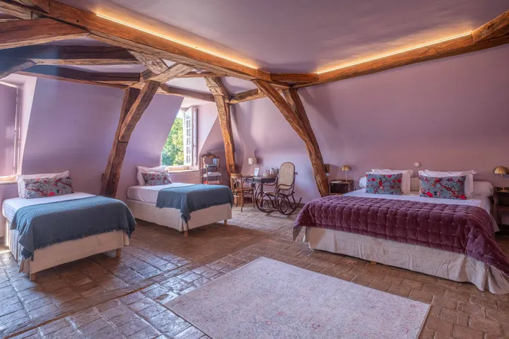 Family room under roof timbers, two double beds and a rug on the floor