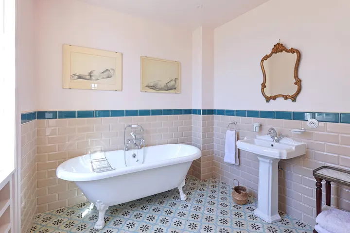 Bagno d'epoca, vasca con piedini e piastrelle con fregio blu
