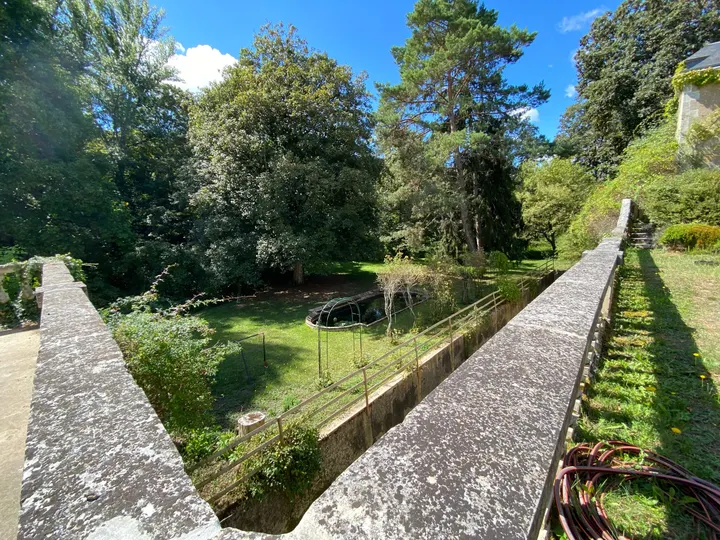 Pont de pierre et balustrade franchissant le jardin en contrebas