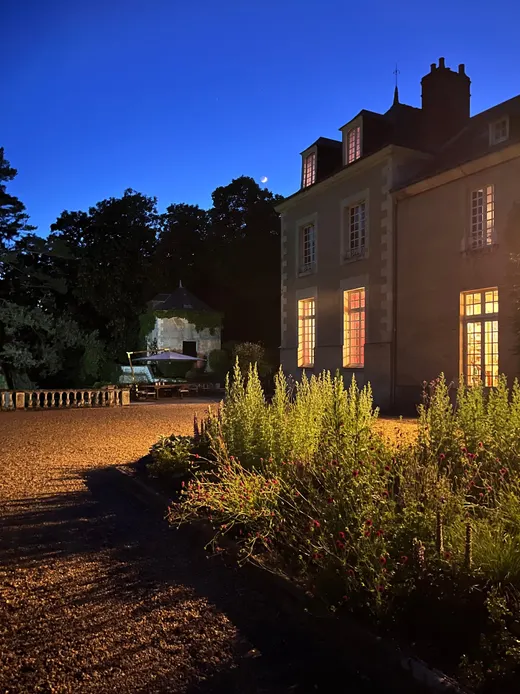 Le château au crépuscule, fenêtres éclairées et allée de gravier