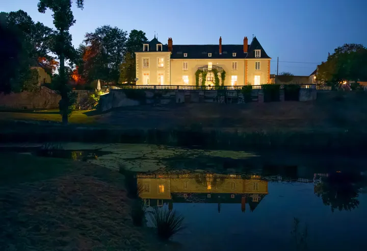 Il castello illuminato di notte, la facciata riflessa nello stagno
