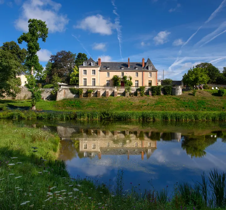 Le château se reflète dans l'étang du parc, un jour d'été