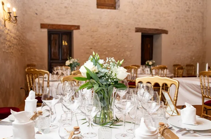 Reception table laid with crystal glasses, a white bouquet and gilt chairs