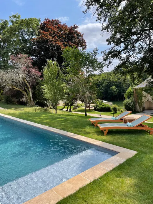 La piscine chauffée dans le parc, transats posés sur la pelouse