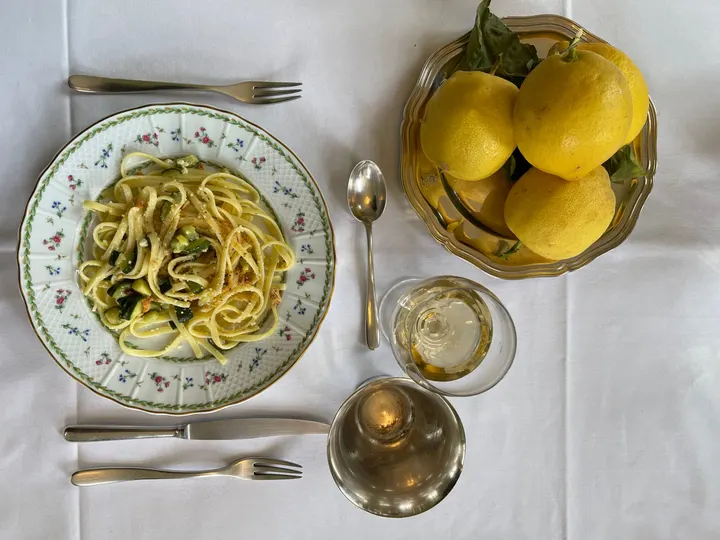 Assiette de pâtes fraîches au citron, citrons entiers dans une coupe à côté