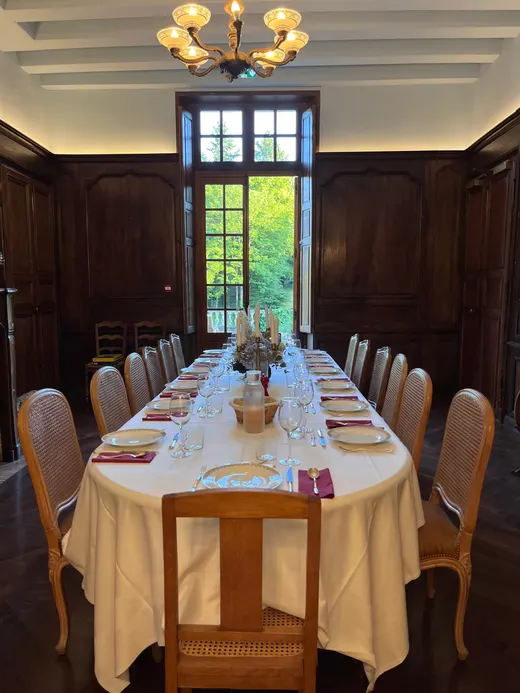 Tavolo apparecchiato nella sala da pranzo in legno, porta aperta sul parco