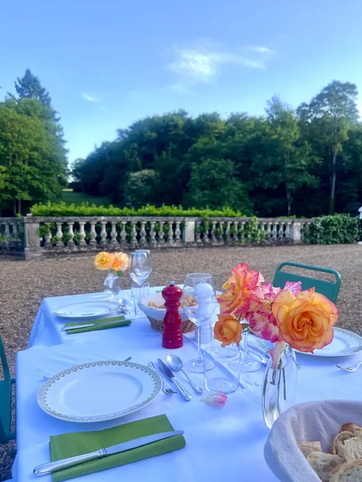 Table dressée en extérieur sur la terrasse, nappe blanche et fleurs orange