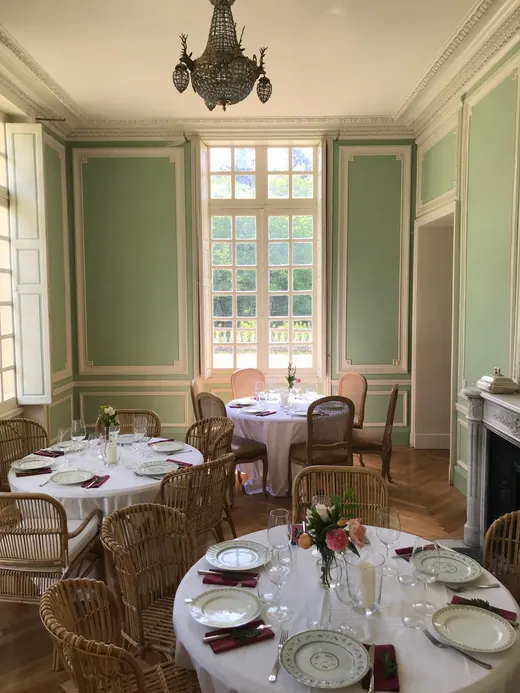 Salle à manger aux boiseries vert d'eau, tables rondes dressées près de la cheminée