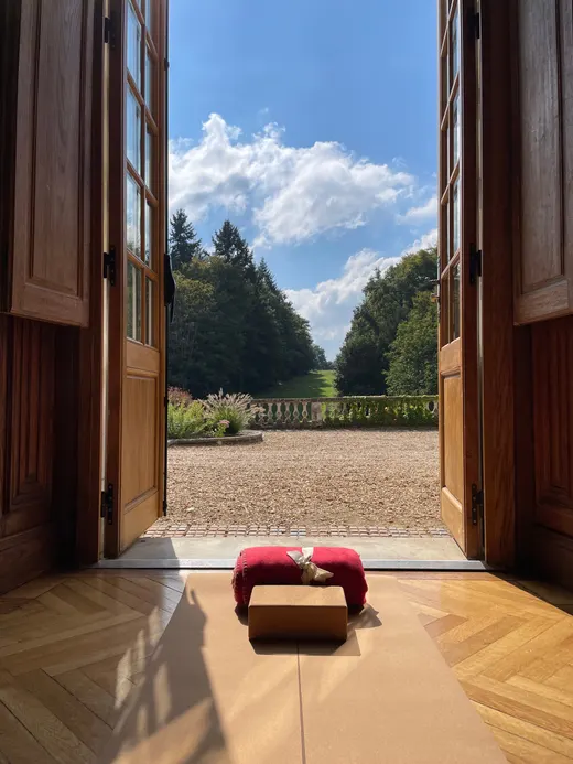 Portes-fenêtres grandes ouvertes sur le parc, tapis et coussins posés au sol