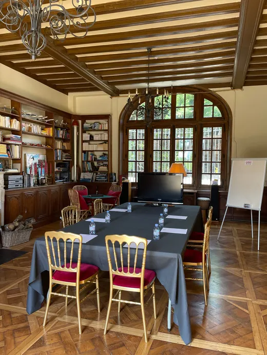 Salle de travail installée en U face aux fenêtres, murs tapissés de livres